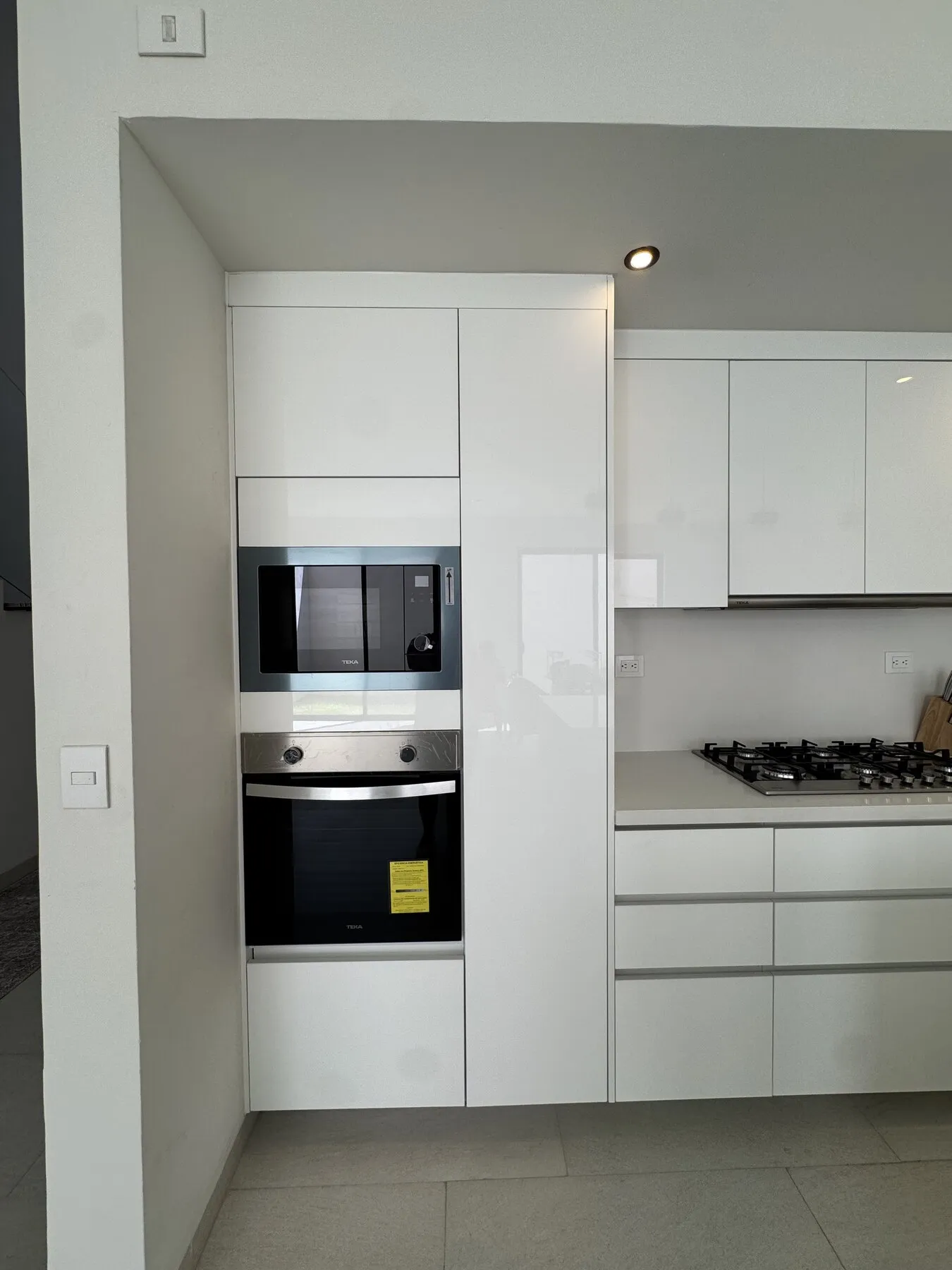 Torre blanca con horno y microondas empotrados junto a la zona de cocción